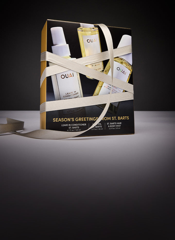 Gift set with OUAI products wrapped in ribbon on a dark background