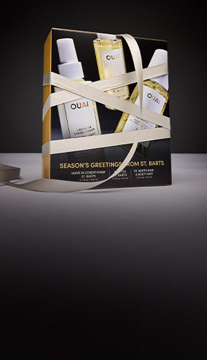 Gift set with OUAI hair products wrapped in ribbon on a dark background