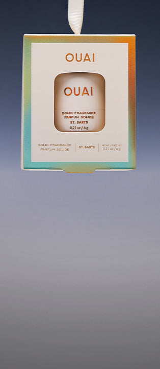 OUAI Solid Fragrance St. Barts box hanging from a white ribbon against a gradient gray background.
