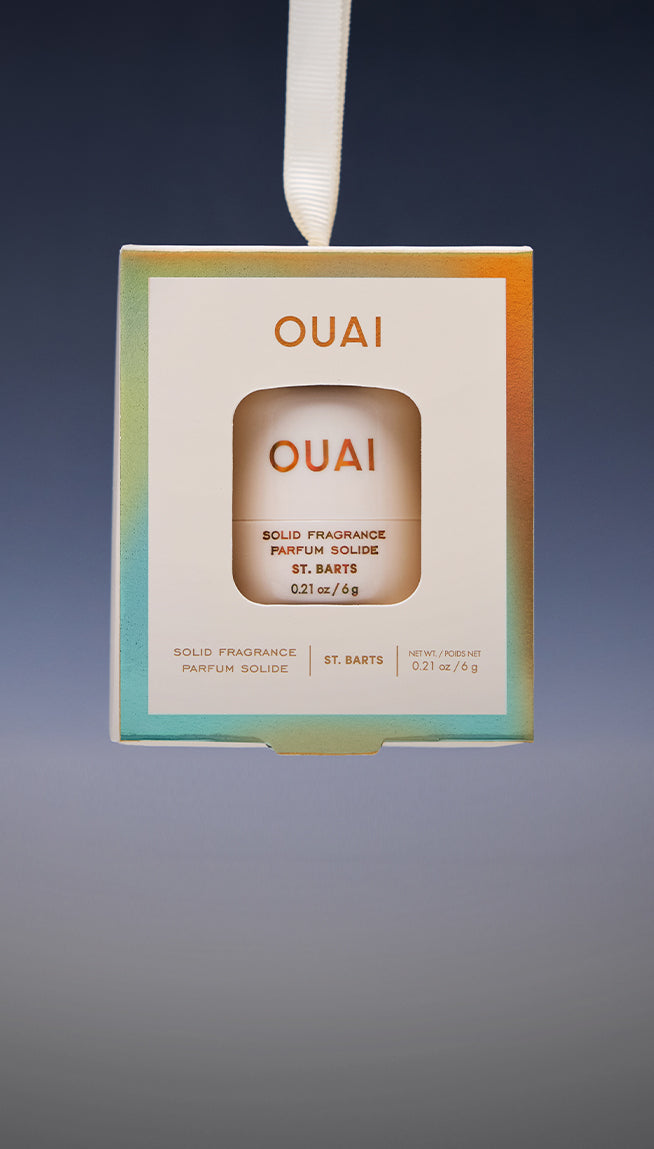 OUAI Solid Fragrance St. Barts box hanging from a white ribbon against a gradient gray background.